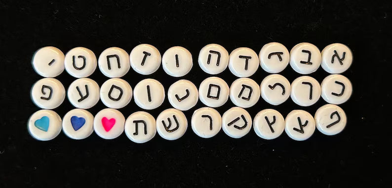 DIY Hebrew letter bracelet making kit by Pretty Beans with seed beads and silver charms, shown with beads and charms on a white background.