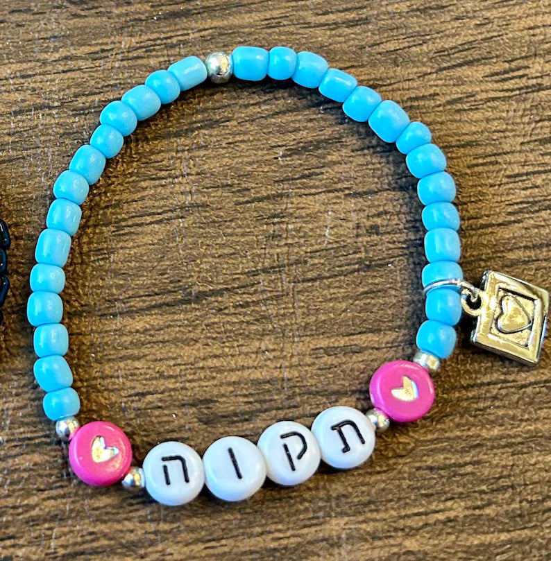 DIY Hebrew letter bracelet making kit by Pretty Beans featuring seed beads and silver charms for creating personalized jewelry.
