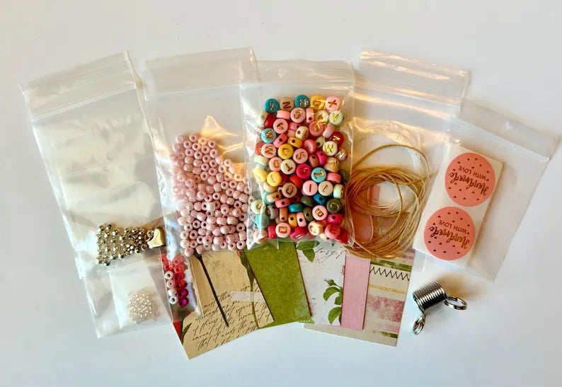 DIY jewelry kit by Pretty Beans featuring seed beads, alphabet beads, and silver plated charms for bracelet making.
