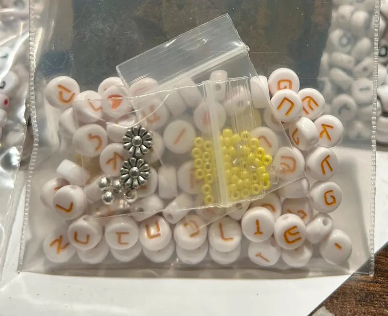 Set of 81 yellow Hebrew letter beads, 7mm, with tiny heart spacers and silver-plated accents for jewelry making.