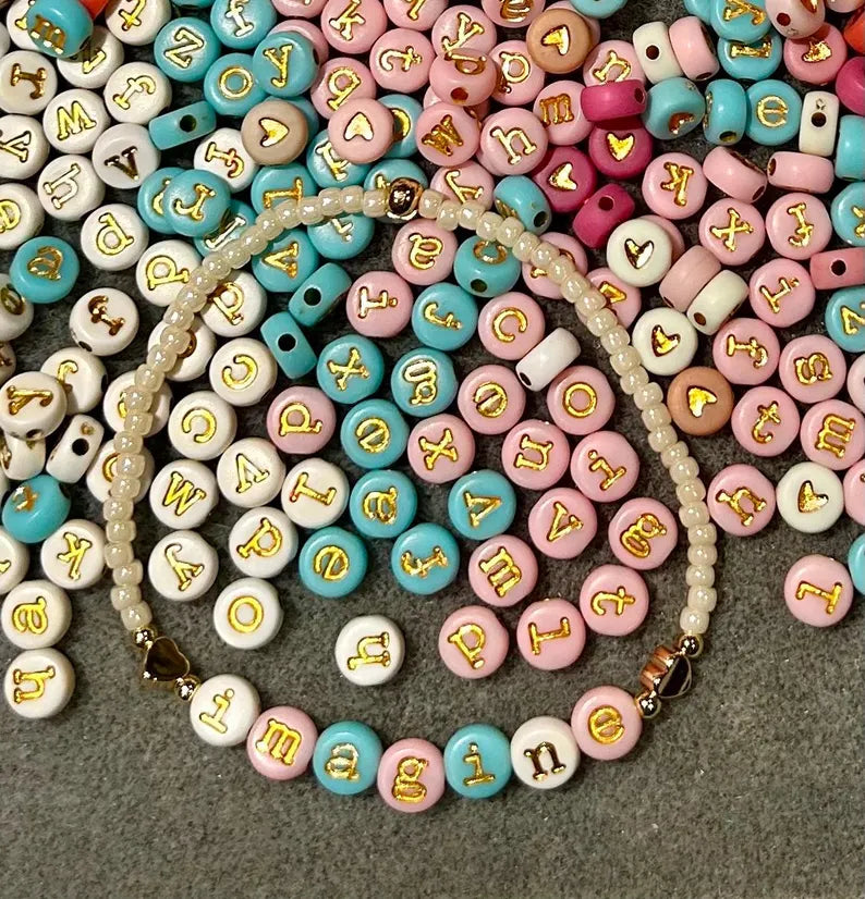 DIY jewelry kit by Pretty Beans featuring seed beads, letter and silver charms for making mini bracelets.
