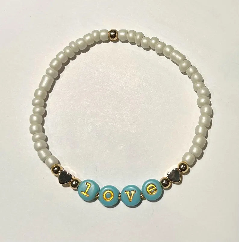 Gold lowercase alphabet beads with 7mm typewriter font, perfect for jewelry making, featuring the Pretty Beans brand name.
