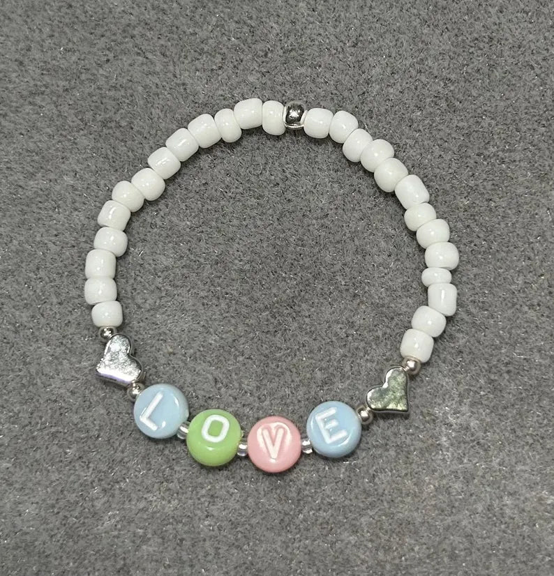 DIY jewelry kit by Pretty Beans featuring seed beads, alphabet beads, and silver-plated charms for bracelet making.