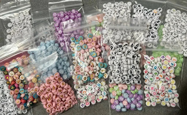 DIY jewelry kit by Pretty Beans with seed beads, letter and silver charms for making mini bracelets.