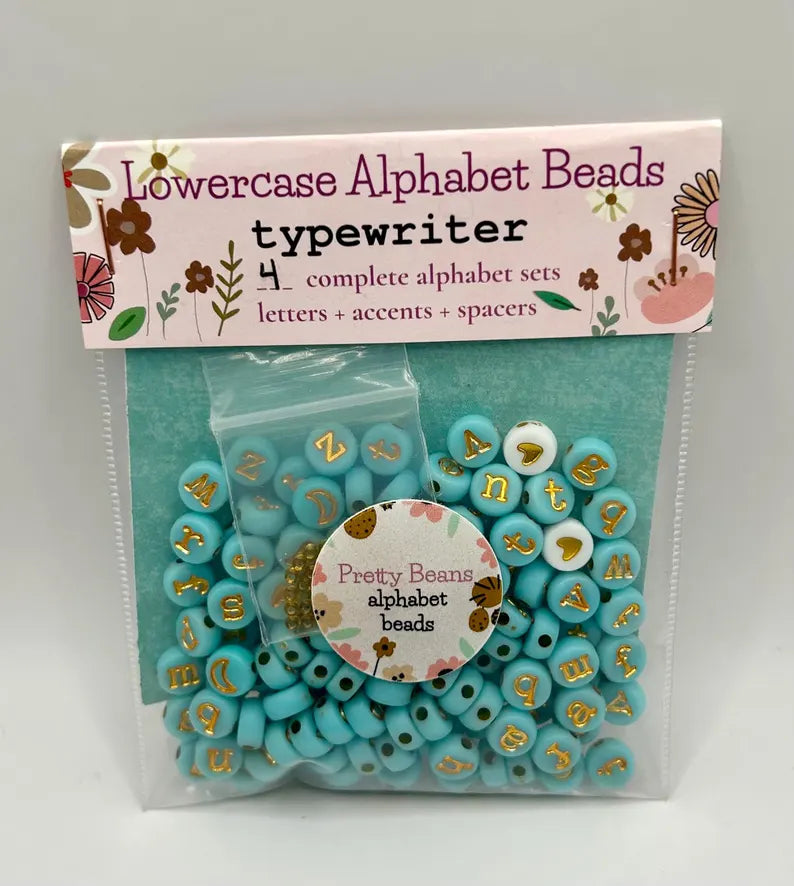 Lowercase gold alphabet beads with 7mm typewriter font, ideal for jewelry making, displayed in a close-up shot.