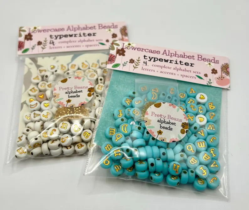 Gold lowercase alphabet beads with 7mm typewriter font for jewelry making, shown in close-up image.