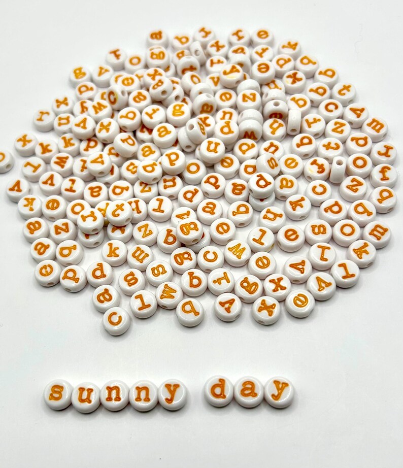 Yellow lowercase alphabet beads with 7mm typewriter font, shown in a close-up image highlighting the beads' round shape and engraved letters.