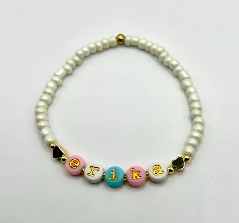 Lowercase gold alphabet beads with 7mm typewriter font used for jewelry making, shown on a string in this image.