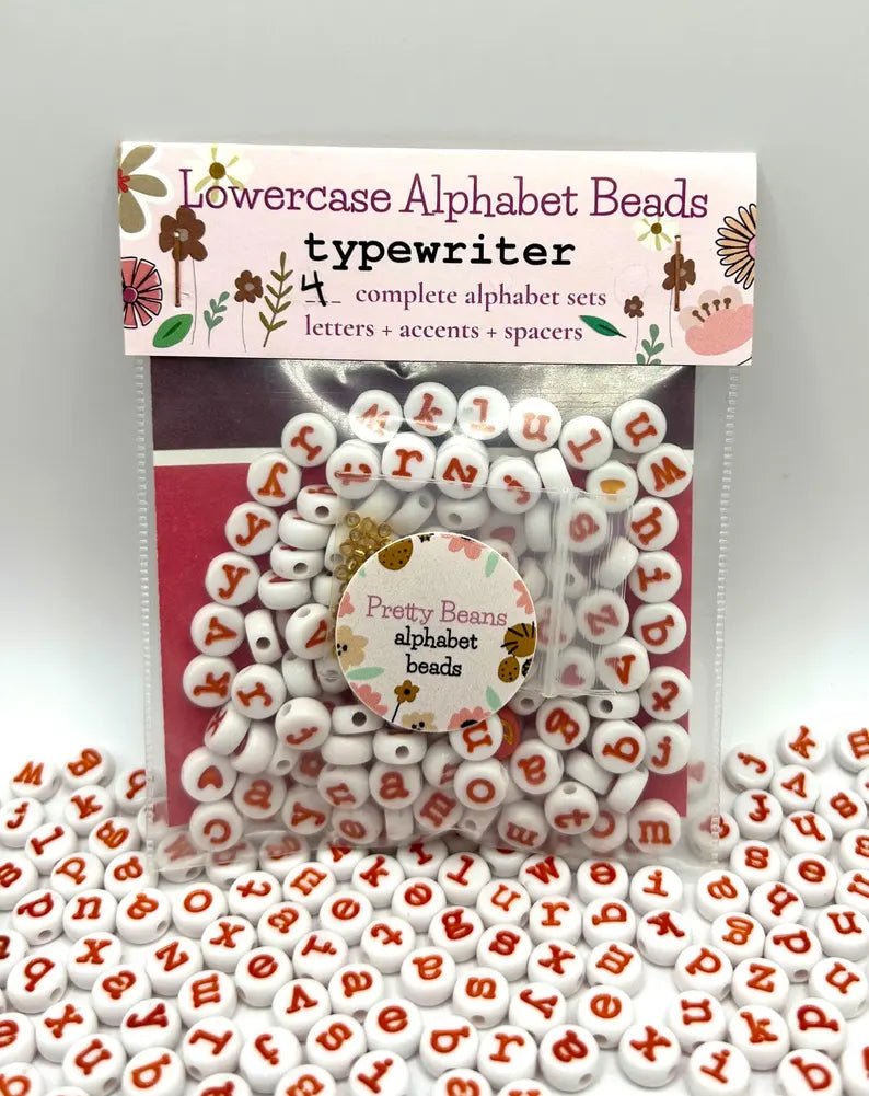 Lowercase orange typewriter font alphabet beads by Pretty Beans for jewelry making, shown in close-up detail.