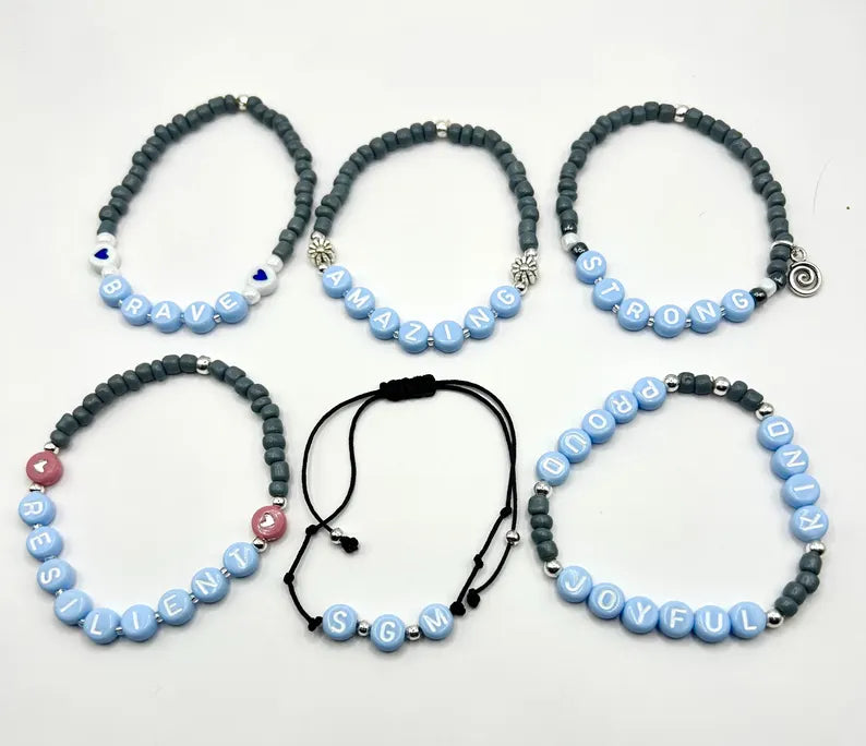 DIY jewelry kit by Pretty Beans with seed beads, letter charms, and silver charms for making mini bracelets.