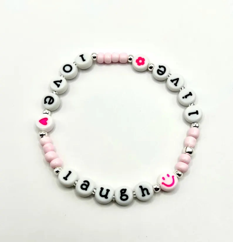 White lowercase alphabet beads with black letters, 7mm size, for jewelry making, by Pretty Beans, shown in close-up.