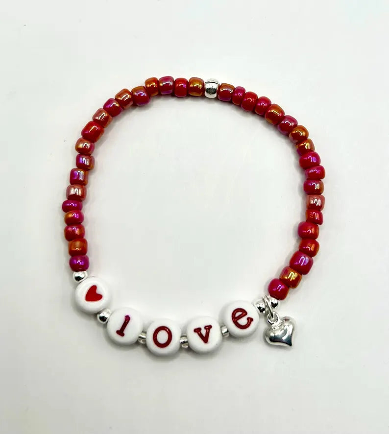 Red alphabet beads with silver accents for jewelry making, featured by Pretty Beans in a close-up image.