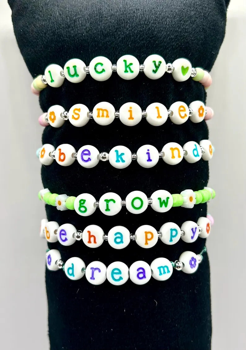 DIY jewelry kit by Pretty Beans with seed beads, letter charms, and silver charms for making mini bracelets.