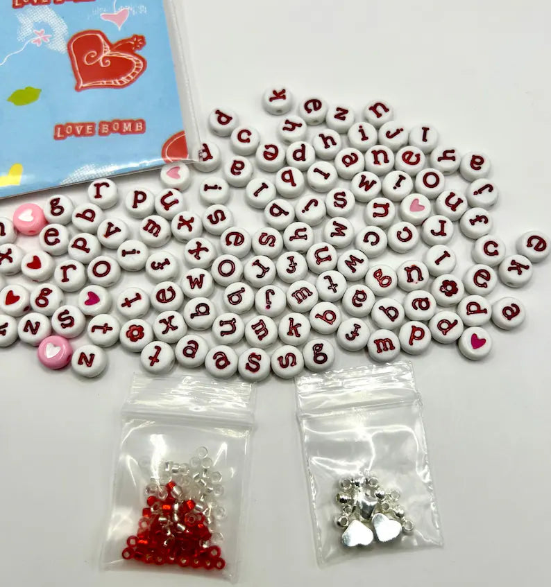 Red alphabet beads with silver accents for jewelry making, featured by Pretty Beans in a close-up image.