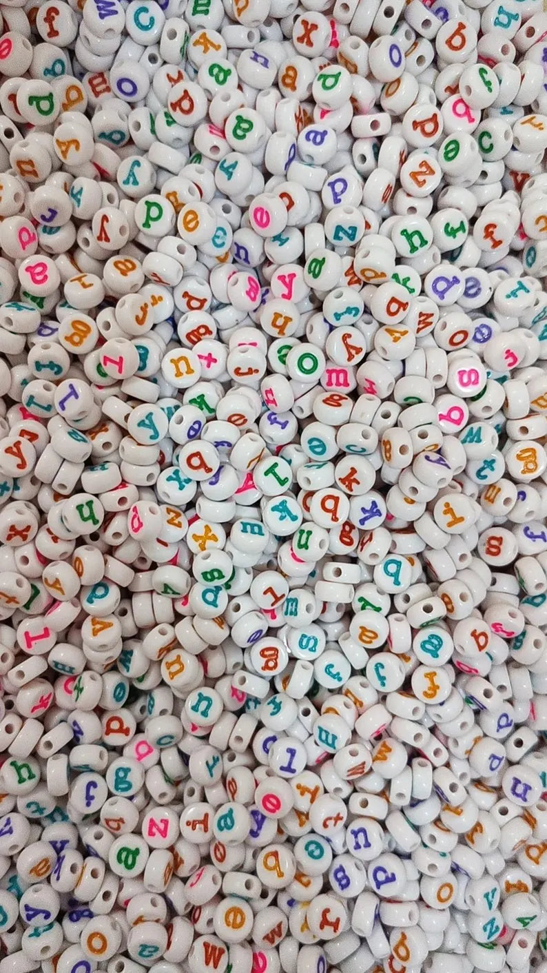 Lowercase gold alphabet beads with 7mm typewriter font, perfect for jewelry making, shown in a close-up image.