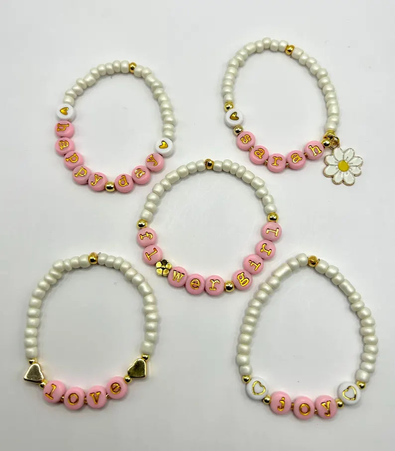 DIY jewelry kit by Pretty Beans featuring seed beads, letter charms, and silver charms for making mini bracelets.